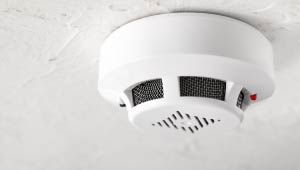 A picture of a white smoke detector mounted to a ceiling.