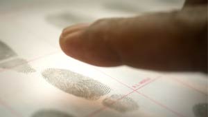 A picture of a finger being fingerprinted onto a fingerprint book.