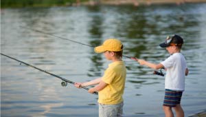 A picture of two kids fishing at a body of water.