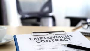 A picture of an employee contract on a clipboard located in an office room like setting.
