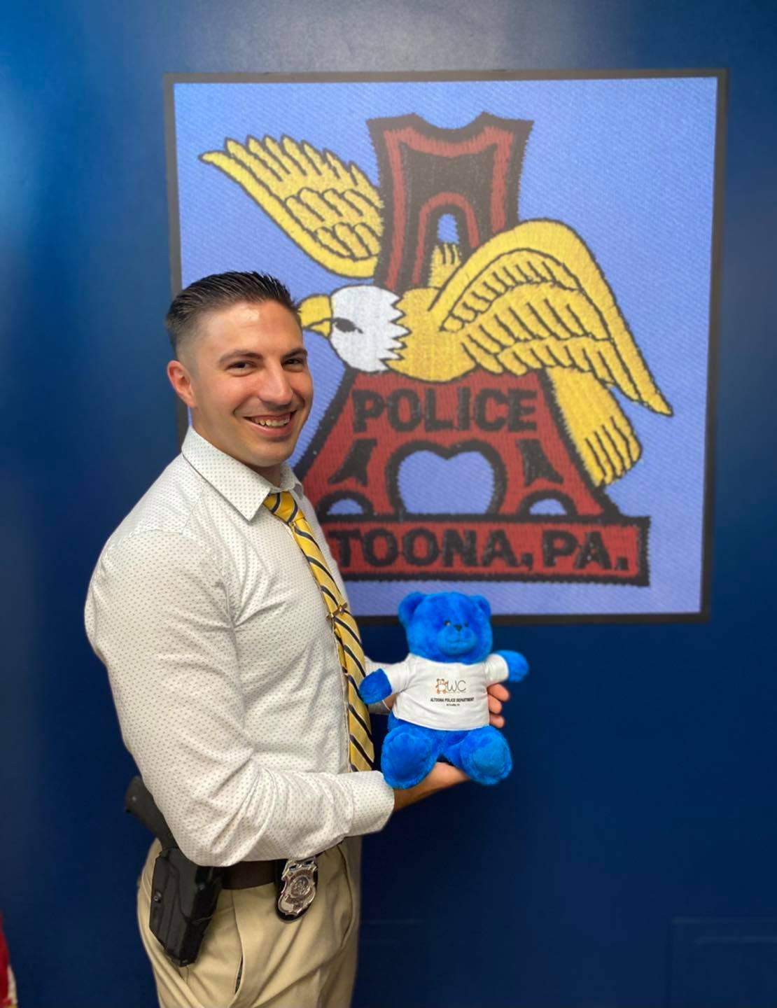 APD officer posing with a stuffed BWC bear.